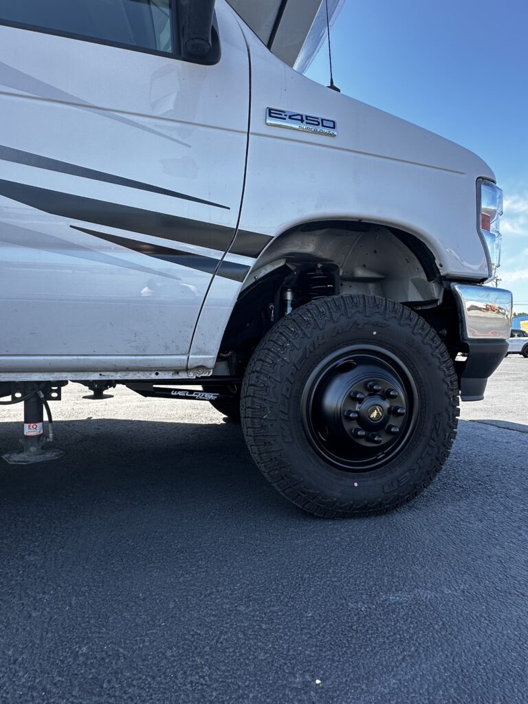 Close-up of WeldTec suspension lift components installed on a Ford Econoline Class C RV.